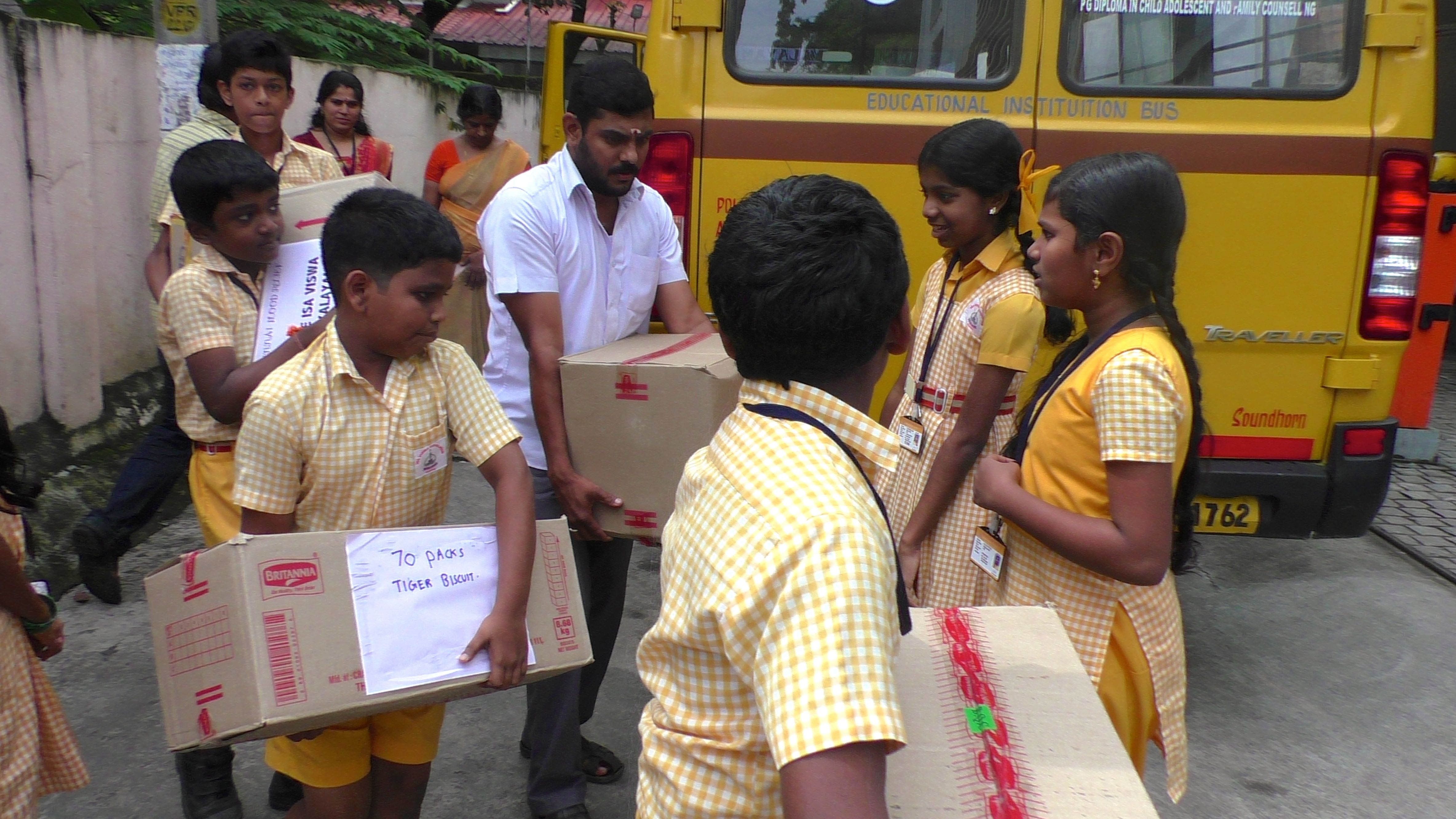 Students of Isa Viswa Vidyalayam unload materials for Chennai relief